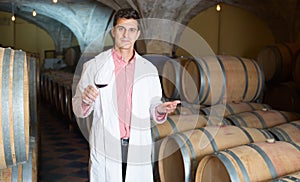 Professional man checking ageing process of red wine