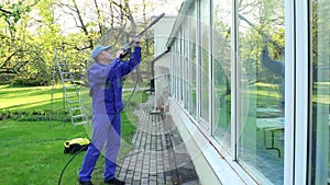 Professional man cleaning dirty windows with high pressure water jet
