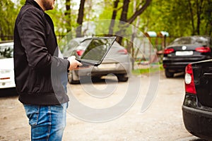 Professional man with a laptop in car tunes tuning control system