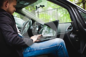 Professional man with a laptop in car tunes tuning control system