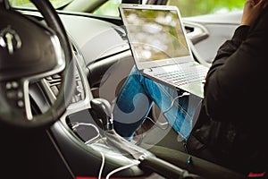 Professional man with a laptop in car tunes tuning control system, updating software, gaining access through to computer