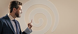 Professional man in suit sideway keep finger pointing up grey background copy space, idea. Man face portrait, banner
