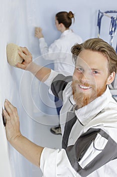 Professional man using sponge float on wall