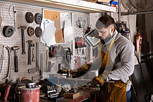 Professional man worker during work with steel in workshop