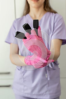 Professional manicure master in purple uniform holds nail varnish bottles. Manicurist and pedicurist waiting for clients