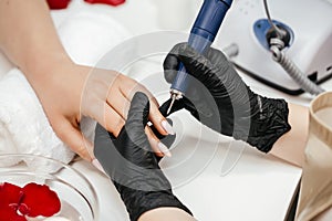 Professional manicure master uses electric machine. hands during manicure. Clipping nails, hand care and nailcare at photo