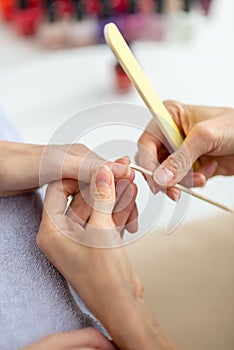 Professional manicurist cleaning cuticle from behind a nail photo