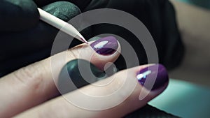 Professional manicurist, manicure work in black gloves at the beauty salon. Dark purple, beautiful pink nails, close up shot