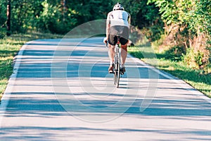 Professional marathon cyclist wearing all of his safety gear rides his bike in the green nature