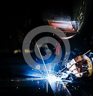 Professional mask protected welder man working on metal welding and sparks metal