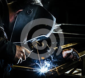 Professional mask protected welder man working on metal welding and sparks metal