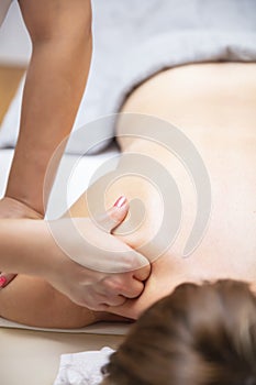 Professional masseur doing massage shoulder of a young woman