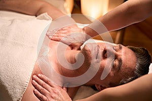 Professional massotherapist treating adult man for cervicalgia photo