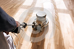 A professional master cleans the floor with a polishing machine