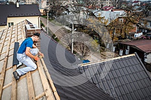 A professional master roofer with electric screwdriver covers repairs the roof