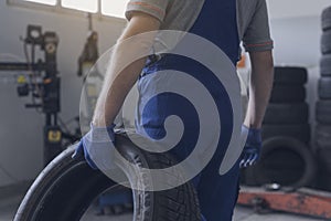 Professional mechanic carrying a tire