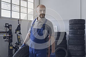 Professional mechanic carrying a tire