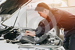 professional mechanic male work tune engine ignition timing in ecu with laptop computer in auto service garage racing shop