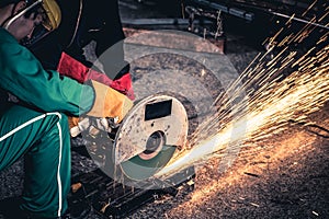 Professional mechanic man is cutting steel metal with rotating carbon blade