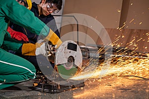 Professional mechanic man is cutting steel metal with rotating carbon blade