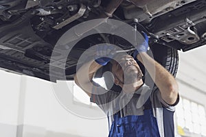 Professional mechanic working under a car