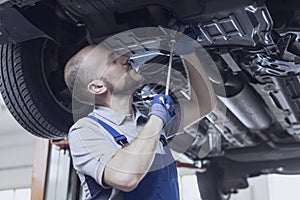 Professional mechanic working under a car