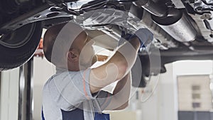 Professional mechanic working under a car