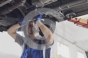 Professional mechanic working under a car