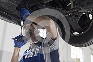 Professional mechanic working under a car