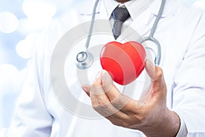 Professional medical doctor holding a red heart ball on blur off