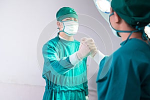 Professional medical doctors performing surgery. Doctors team soul brother handshake, thumb clasp handshake or homie handshake,