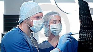 Professional medical doctors working in emergency medicine. The surgeon and the nurse is monitoring x-ray of a patient.