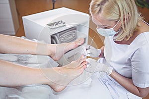 Professional medical pedicure procedure close up using double nail instrument. Patient visiting chiropodist podiatrist. Foot