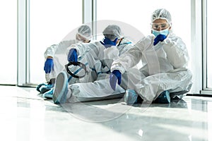 Professional medical team in Personal Protective Equipment or PPE cloth sitting and so tried after treat patients infected with