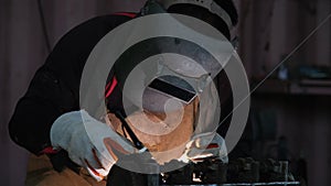 Professional men wearing welding mask and gloves work in home workshop with arc welding and argon.