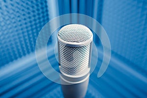 Professional microphone in sound recording studio, blue acoustic foam background