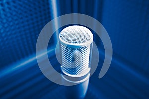 Professional microphone in sound recording studio, blue acoustic foam background