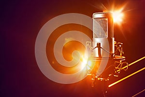 Professional microphone on the stage with orange light beams. Live music, concert or entertainment