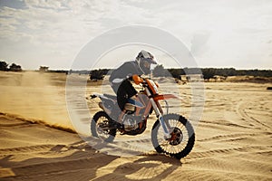 Professional motocross rider driving on sand dune