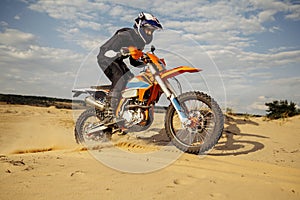 Professional motocross rider driving on sand dune