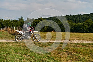 A professional motocross rider exhilaratingly riding a treacherous off-road forest trail on their motorcycle.