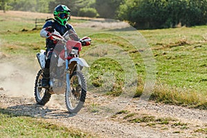 A professional motocross rider exhilaratingly riding a treacherous off-road forest trail on their motorcycle.