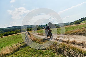 A professional motocross rider exhilaratingly riding a treacherous off-road forest trail on their motorcycle.