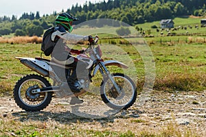 A professional motocross rider exhilaratingly riding a treacherous off-road forest trail on their motorcycle.