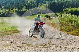 A professional motocross rider exhilaratingly riding a treacherous off-road forest trail on their motorcycle.