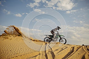 Professional motocross rider sliding down sand hill