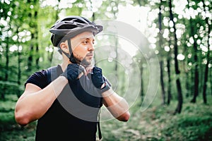 Professional mountain bike rider, cyclist preparing protection helmet during workout