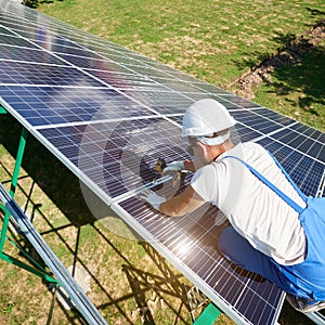 Professional mounter installing solar batteries on green metallic carcass.