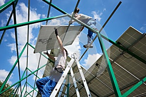 Professional mounters team installing solar batteries on metallic carcass.