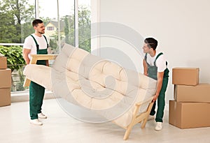 Professional movers carrying sofa in house